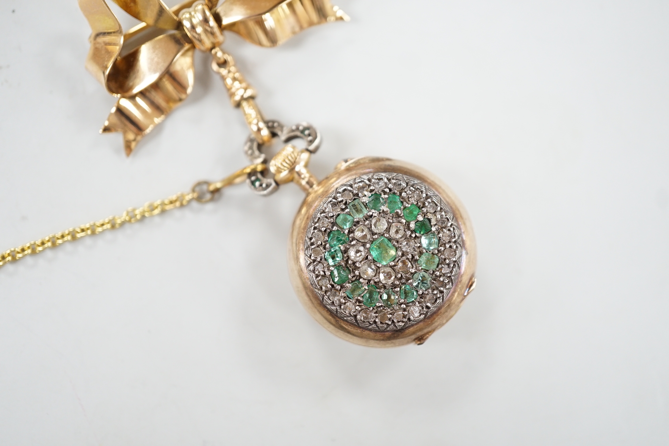 A lady's late 19th century French? yellow metal, emerald and rose cut diamond cluster set fob watch, diameter 24mm, suspended from a late Victorian 9ct gold ribbon bow brooch, gross weight 17.1 grams.